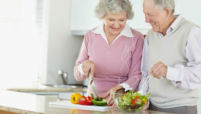 casal de idosos felizes prepara refeição na cozinha